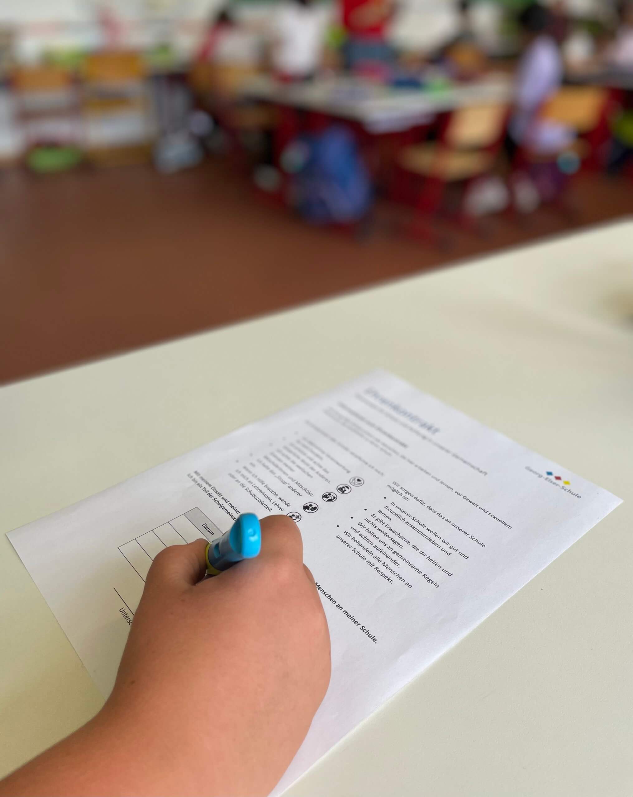 Ein Schulkind unterzeichnet den Vertrag zum Schutzkonzept der Georg-Elser-Schule